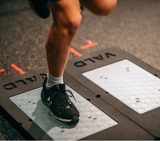 Athlete's feet on VALD ForceDecks dual force plates in a dark performance gym